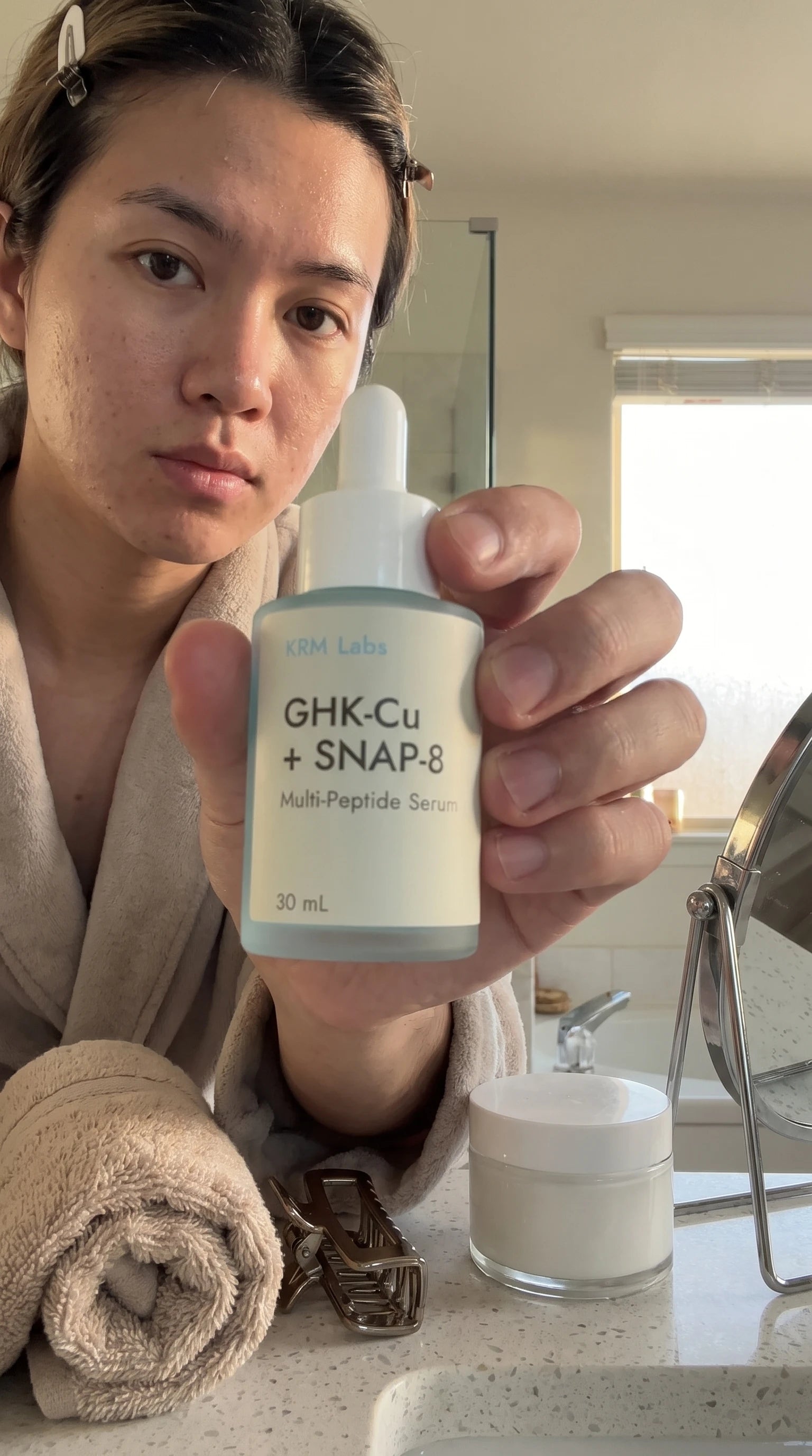 Customer holding KRM Labs serum bottle over bathroom sink