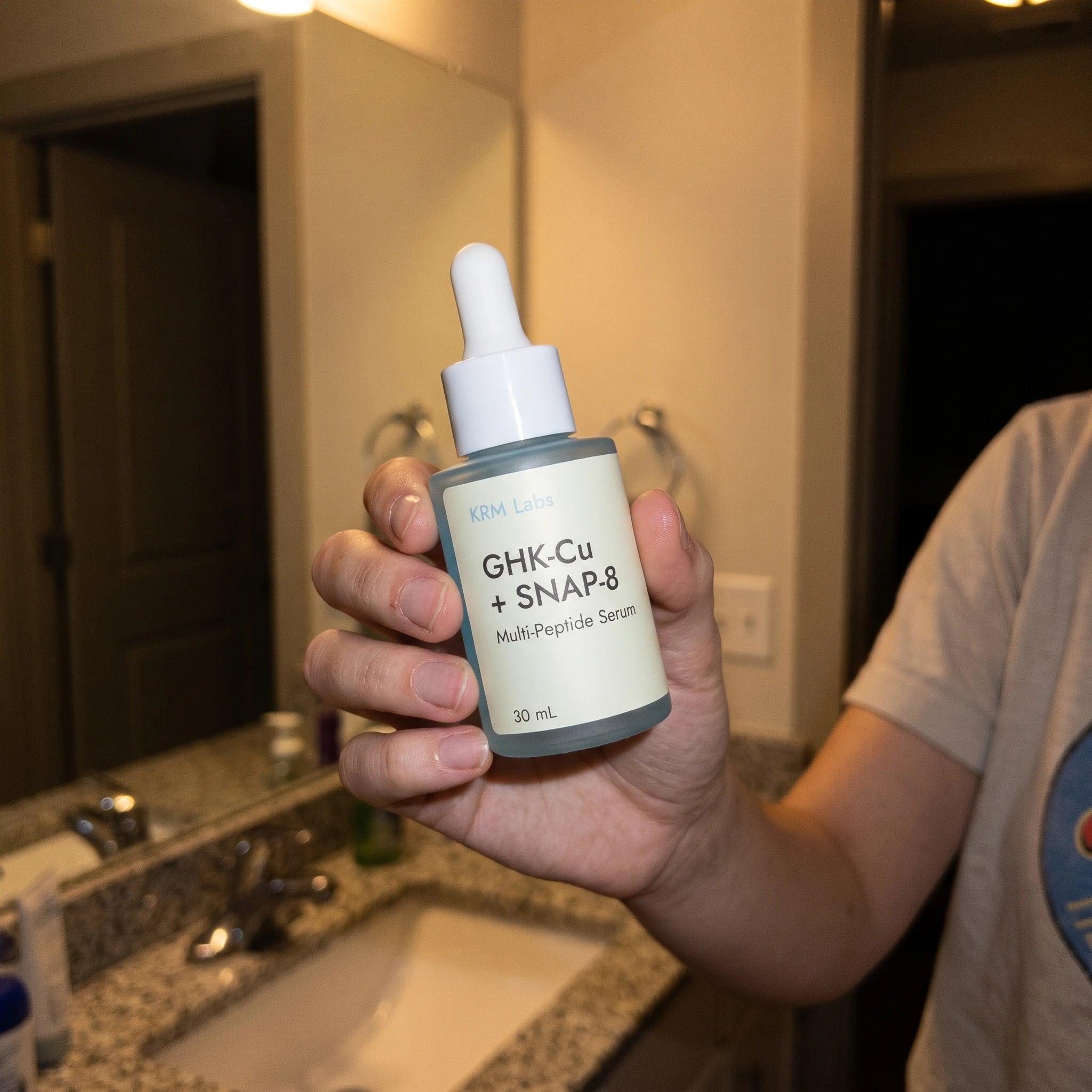 Customer holding KRM Labs serum bottle at night