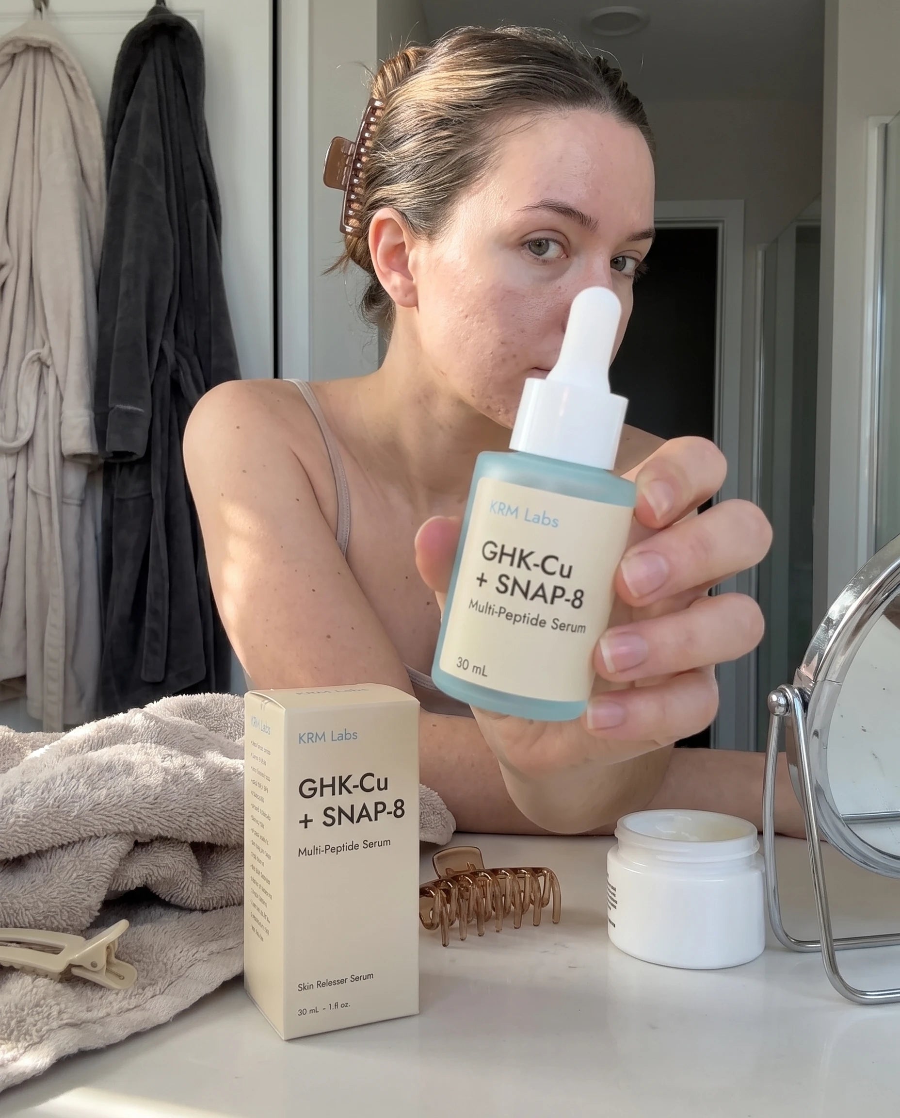 Customer holding KRM Labs serum and box in bathroom
